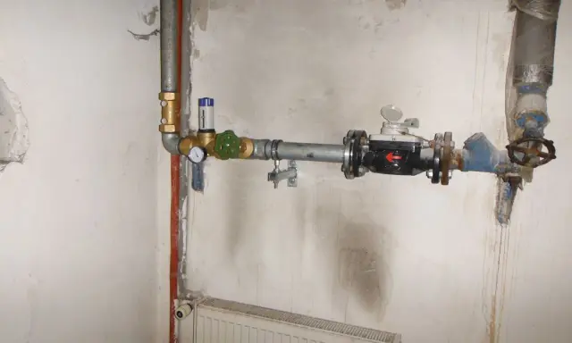 Instalacja wodna z widocznym elementem pokazującym, jak działa reduktor ciśnienia wody, z manometrem i zaworem.