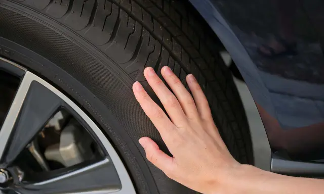 Una mano toca la banda de rodadura de un neumático, sugiriendo la pregunta de cuánto duran las ruedas de un coche.