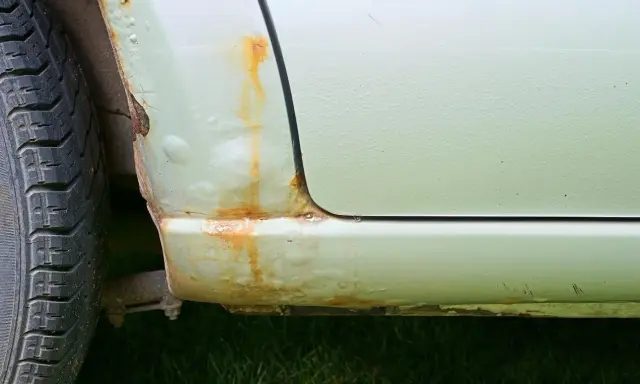 Rdza na progu samochodu i pęcherze pod lakierem. Aby zapobiec korozji, należy regularnie konserwować auto.