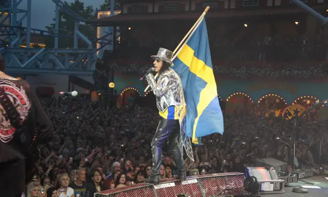 Alice Cooper i Sverige, med svensk flagga och en stor publik som filmar.