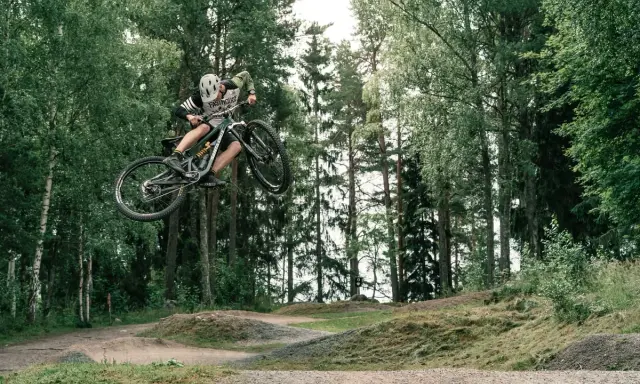 Mountainbike-åkare flyger genom luften i en skogspark nära Stockholm.
