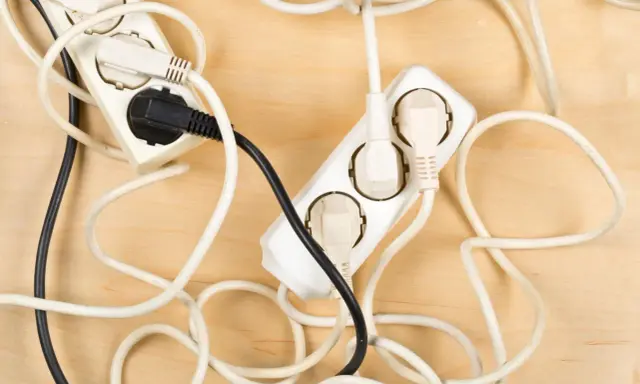 Chaotische Kabel und Steckdosen auf Holz. Hier sind einige kabel verstecken ideen, um Ordnung zu schaffen.
