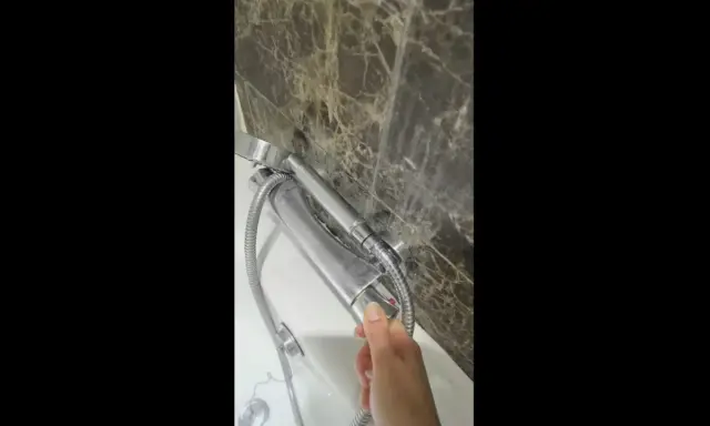 Dłoń reguluje uchwyt baterii termostatycznej, by uzyskać idealną temperaturę ciepłej wody.
