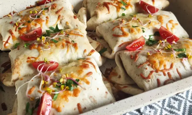 Tortilla z mięsem mielonym i serem, zapieczona z pomidorkami i kiełkami. Pyszne danie gotowe do podania.
