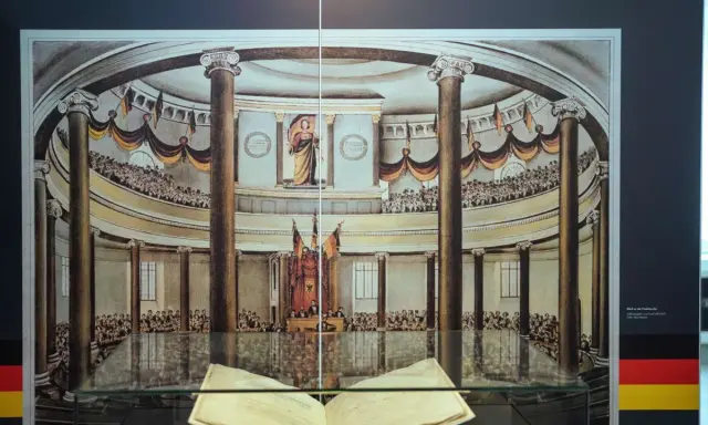 Blick in die Paulskirche, wo 1849 die Paulskirchenverfassung verabschiedet wurde. Viele Menschen verfolgen die Debatten.