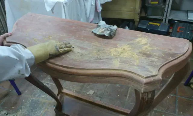 Proceso de como decapar un mueble antiguo, lijando la superficie para eliminar la pintura vieja.