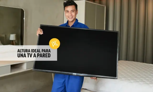 Hombre sonriente sostiene un televisor, listo para instalarlo. La altura ideal para un mueble de TV suspendido es clave.
