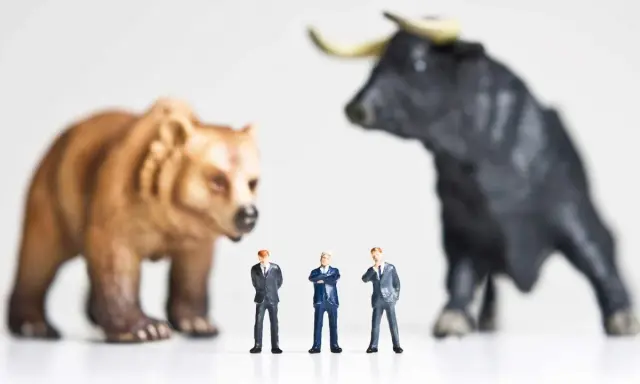 Miniature businessmen stand between a bear and a bull, symbolizing market volatility and the quest for art investment returns.