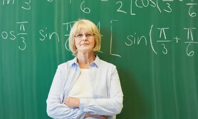 Nauczycielka matematyki przed tablicą z równaniami. Czy doczekamy się wcześniejszych emerytur dla nauczycieli?