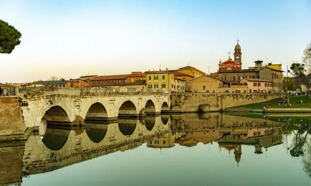 Ponte di Tiberio a Rimini, un luogo che evoca la magia di Fellini, con le sue arcate che si specchiano nell'acqua calma.