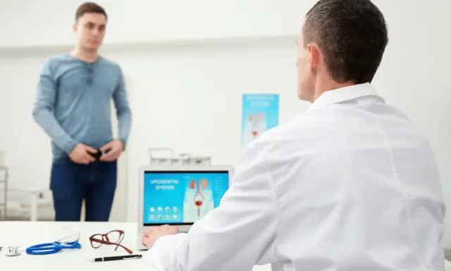 Lekarz omawia z pacjentem problemy z zatrzymaniem moczu po operacji prostaty, analizując na ekranie laptopa układ moczowo-płciowy.
