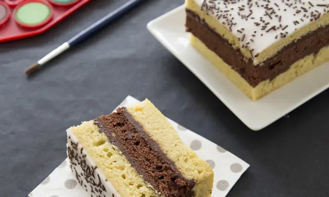 Gâteau napolitain, le meilleur pâtissier. Une part sur une serviette, une autre entière sur une assiette. Pinceau et palette de peinture à proximité.