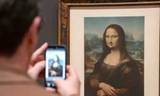 Un visitante fotografía la Mona Lisa con bigote y perilla, una de las obras de arte de Marcel Duchamp, en un museo.