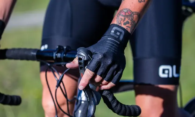 Rowerzysta w czarnych, bezpalczastych rękawiczkach, idealnych na rower, trzyma kierownicę.