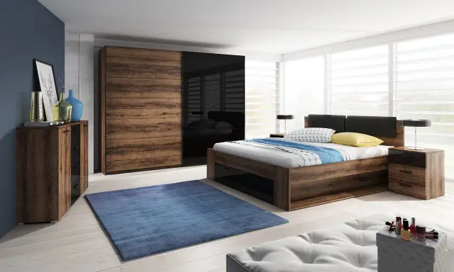 Dormitorio con muebles oscuros de madera y cristal negro. Pared azul oscuro, alfombra azul y cama con ropa de cama blanca y azul.