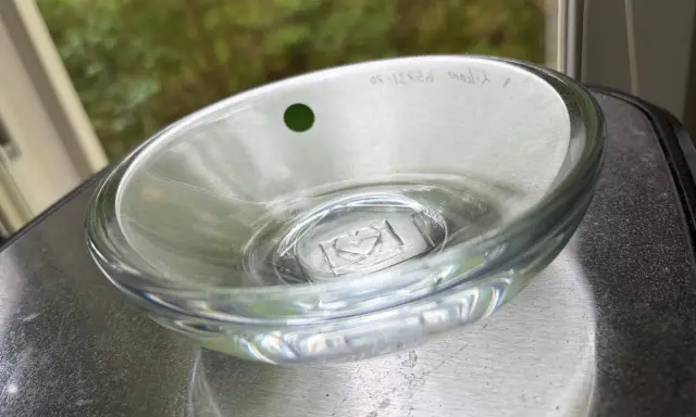 En Orrefors skål, ett tidlöst konstverk. Denna glasdesign med en grön prick och graverad text visar Orrefors skålar genom tiderna.