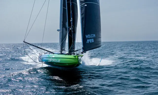 Voilier vert et bleu "Go Circular" naviguant à pleine vitesse, voiles noires marquées "Holcim PRB". Un design de Guillaume Verdier.
