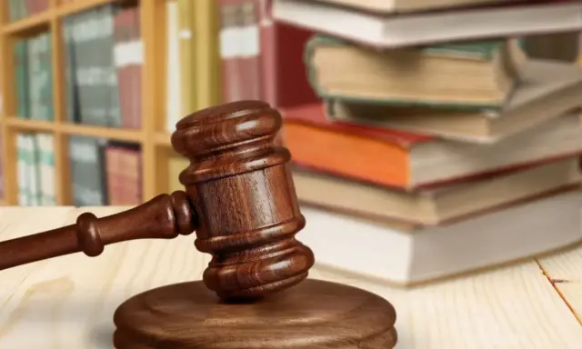 Martelletto da giudice su tavolo di legno, con libri e scaffali sullo sfondo. Simboleggia cosa succede dopo incidente probatorio.