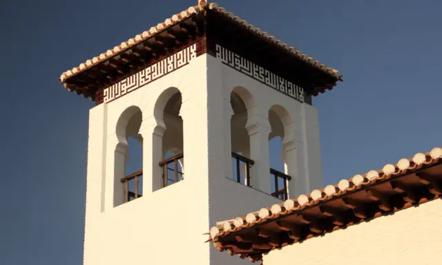 Weiße Moschee in Granada mit arabischer Kalligrafie und maurischen Bögen.