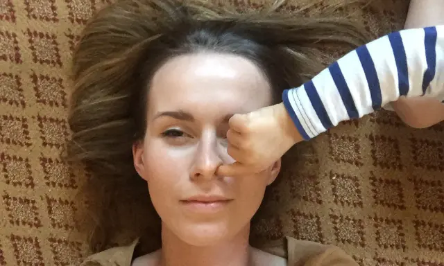 Kiedy mam dość swojego dziecka, jego rączka w paski zasłania mi oko. Leżymy na dywanie.