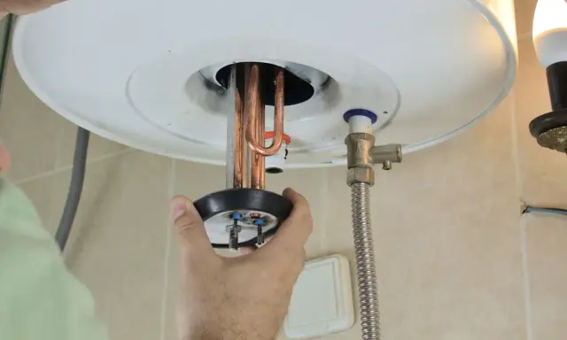 Mano ajustando la resistencia termoeléctrica de un calentador de agua.