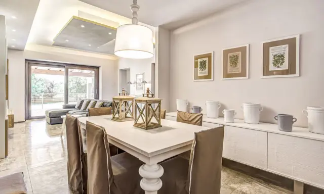 Un'elegante casa stile shabby chic moderno con tavolo da pranzo, divano e quadri botanici.