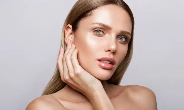 Mujer con piel radiante y labios brillantes, mostrando los pasos para maquillarse con un look natural y elegante.