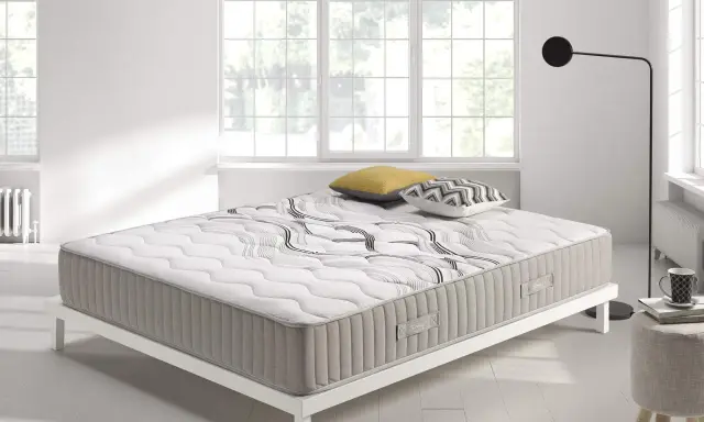 Colchón con diseño moderno sobre base blanca, ideal para quienes buscan confort y soporte. ¿Que es mejor para la espalda muelles o visco?
