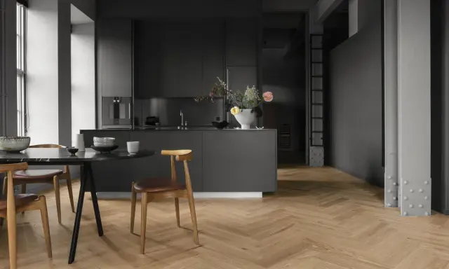Cuisine moderne avec îlot central, chaises en bois et table en marbre. Le parquet en chevrons, bien que beau, est une mauvaise idée pour une cuisine.