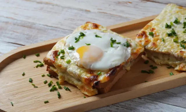 Croque monsieur con huevo frito y cebollino, un delicioso sándwich gratinado.