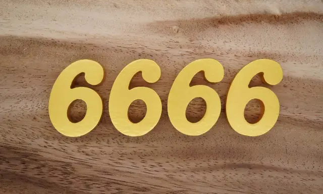 Quatre chiffres dorés 6666 sur fond de bois. Le 6666 signification est souvent lié à l'abondance et à la prospérité.