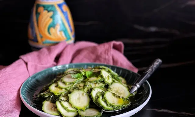 Fette di zucchine marinate crude, condite con erbe aromatiche e olio. Un contorno fresco e leggero, perfetto per l'estate.