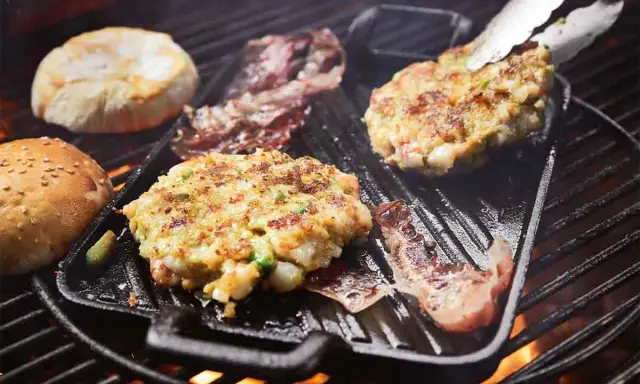 Burger-Patties und Brötchenhälften werden auf einem Grillrost zubereitet. Das Burger grillen verspricht einen köstlichen Genuss.