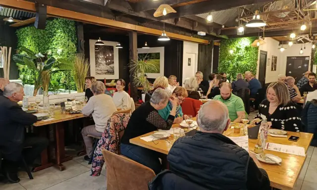 Un dîner convivial dans un restaurant à l'ambiance chaleureuse, où les convives savourent des mets qui incarnent la définition du "produit du terroir".