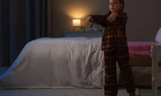 Bambina in pigiama a quadri cammina nel sonno, un esempio di sonnambulismo bambini.