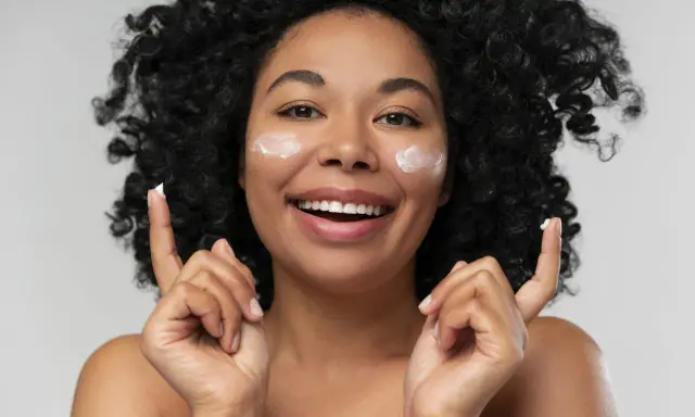 Donna sorridente con crema sul viso. La crema è non comedogeno, significa che non ostruisce i pori.