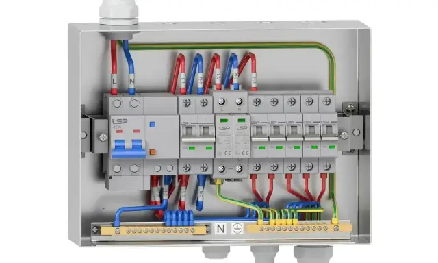 Metalowa obudowa z wyłącznikami i przewodami. Widoczna instalacja elektryczna natynkowa z zabezpieczeniami i listwami zaciskowymi.