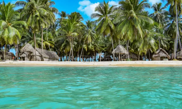 Rajska plaża San Blas z chatkami z liści palmowych i turkusową wodą.