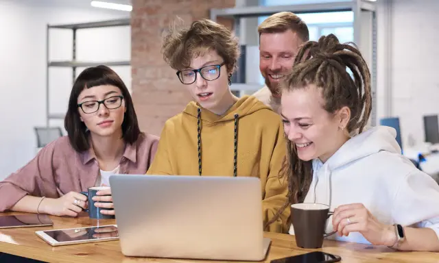Zespół pracuje nad projektem, dyskutując przy laptopie. Może to być ich **praca** jako **ratownik KPP**.