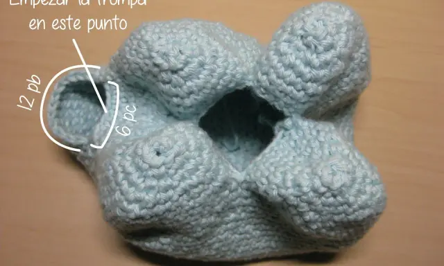 Un elefante amigurumi azul claro, en proceso de tejido. Se indica dónde empezar la trompa.