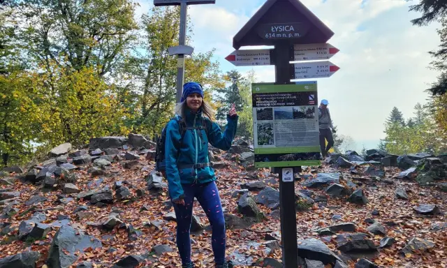 Uśmiechnięta turystka na szczycie Łysicy, 614 m n.p.m. Jesienne liście i kamienie wokół.