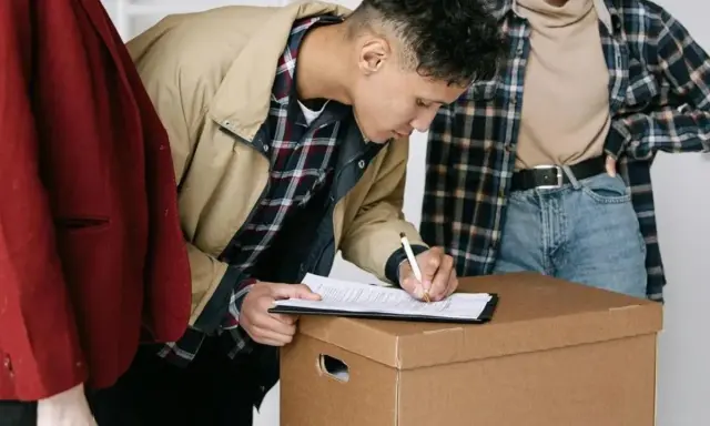 Jóvenes firmando un contrato de mudanza, quizás relacionado con la ley de arrendamientos urbanos.