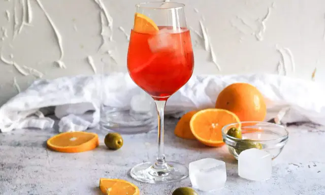 Ein Aperol Spritz mit Orangenscheibe und Eis. Orangen, Oliven und Eiswürfel deuten auf Aperol Spritz Varianten hin.