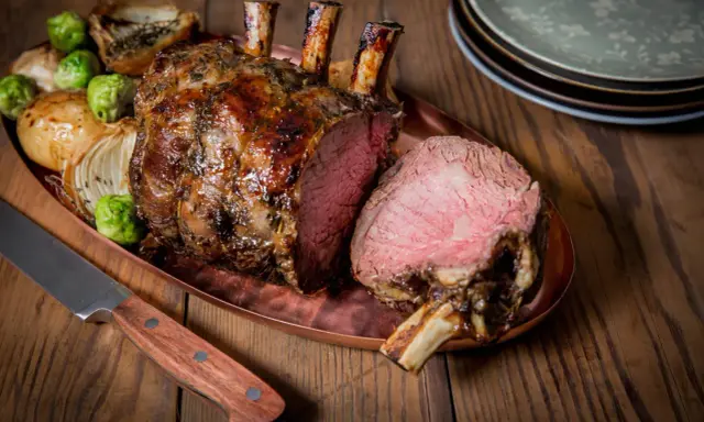 Carré d'agneau rôti 1 kg, saignant, servi avec des oignons et des choux de Bruxelles. Le temps de cuisson est parfait.