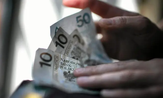 Dłoń trzyma polskie banknoty 10 i 50 zł. Zastanawiasz się, ile pieniędzy na bierzmowanie to odpowiednia kwota?