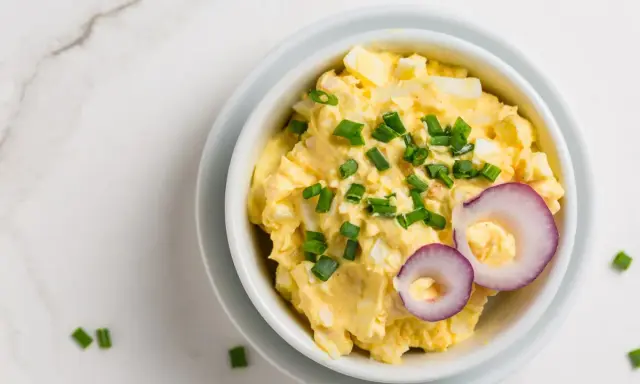 Pyszna pasta jajeczna z serem, posypana szczypiorkiem i ozdobiona krążkami czerwonej cebuli. Idealna na kanapki.