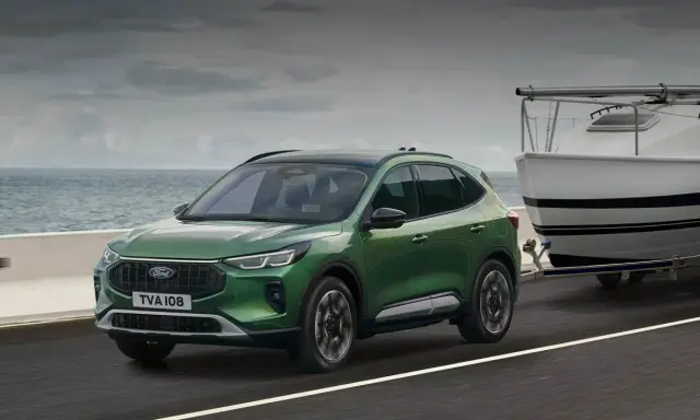 Zielony Ford Kuga z przyczepą i łodzią, idealny na wakacyjne wyjazdy. Sprawdź ford kuga cena!