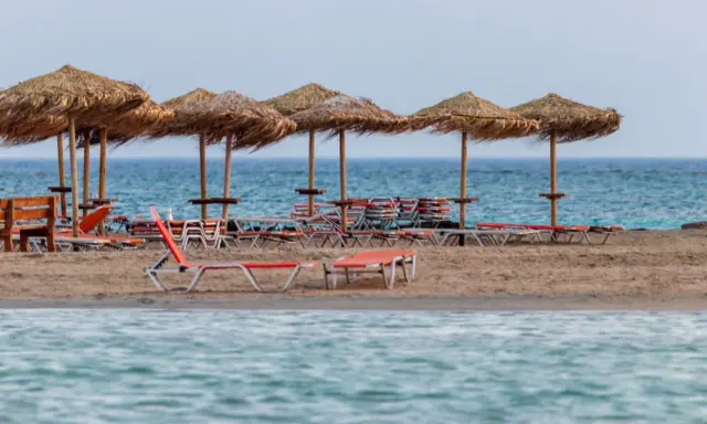Plaża Elafonisi z rzędem słomianych parasoli i leżaków, gotowa na gości.