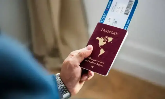 Dłoń trzyma paszport i bilet lotniczy. Czy na Cypr potrzebny jest paszport? Sprawdź przed podróżą!