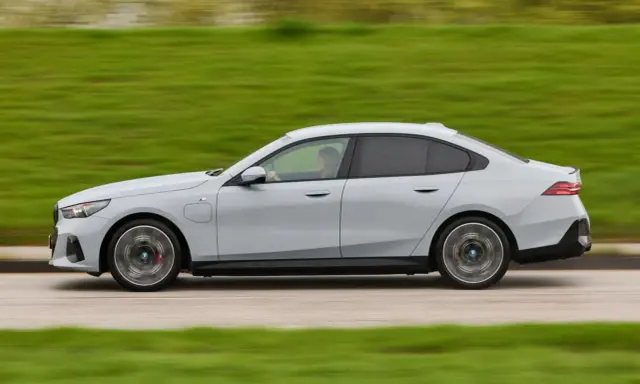 Ein grauer BMW 550e fährt auf einer Straße, die Landschaft verschwimmt im Hintergrund.